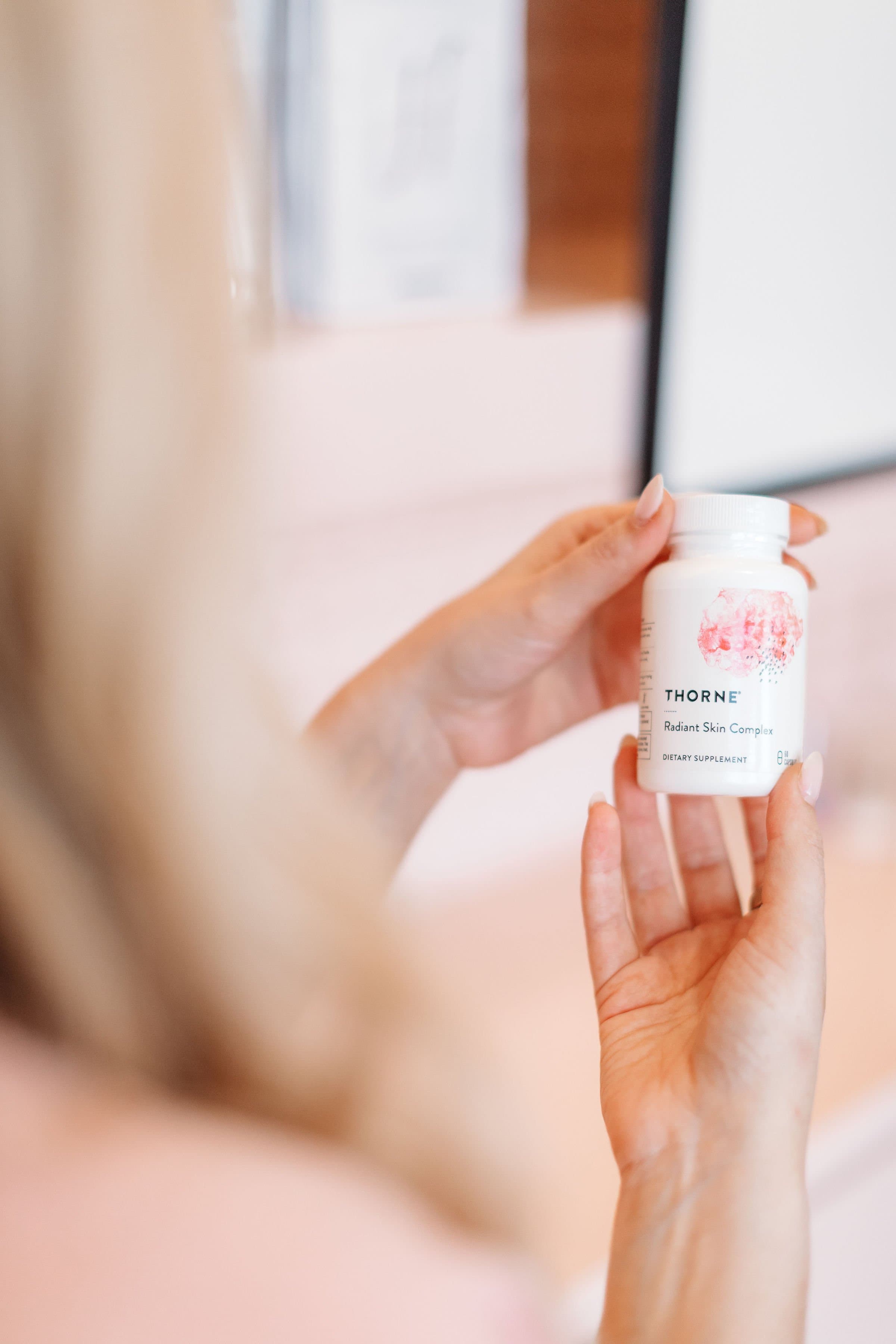 A hand holding a Thorne wellness supplement
